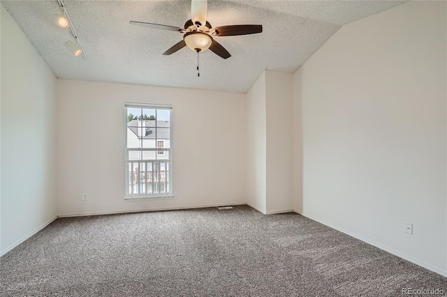 carpeted empty room with lofted ceiling, track lighting, a textured ceiling, and ceiling fan