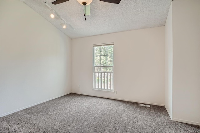 carpeted empty room with ceiling fan, track lighting, and a textured ceiling