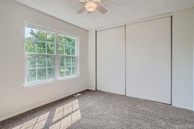 unfurnished bedroom featuring a textured ceiling, a closet, ceiling fan, and carpet flooring