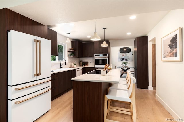 6097 S Jackson St, Centennial, CO 80121 - kitchen with white appliances, dark brown cabinetry, light countertops, light wood finished floors, and recessed lighting