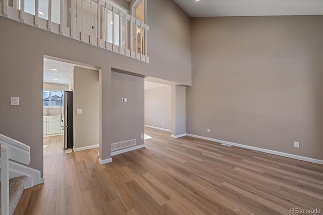 unfurnished living room with a high ceiling and light hardwood / wood-style flooring