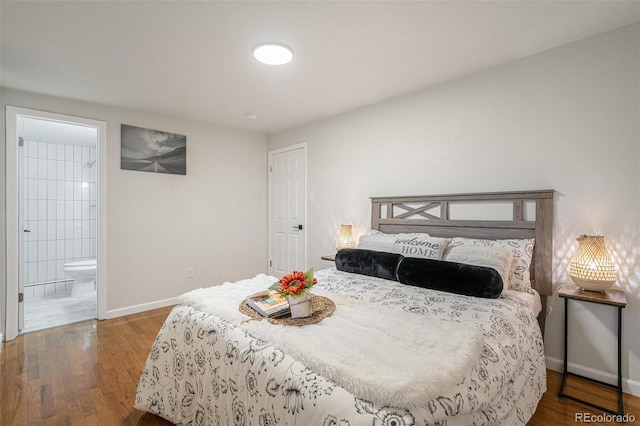 bedroom with connected bathroom and hardwood / wood-style flooring