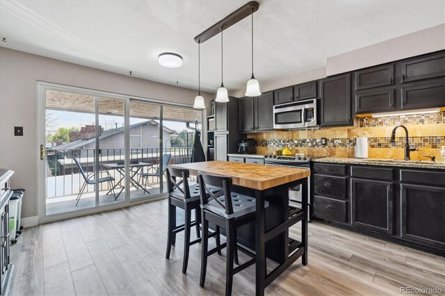 6495 E Happy Canyon Rd Unit 163, Denver, CO 80237 - kitchen with appliances with stainless steel finishes, a sink, light wood-style flooring, and tasteful backsplash