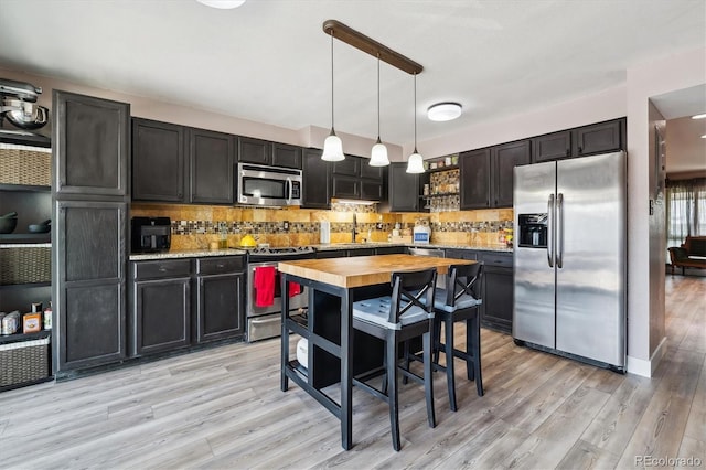 6495 E Happy Canyon Rd Unit 163, Denver, CO 80237 - kitchen featuring stainless steel appliances, light wood-style floors, tasteful backsplash, and hanging light fixtures