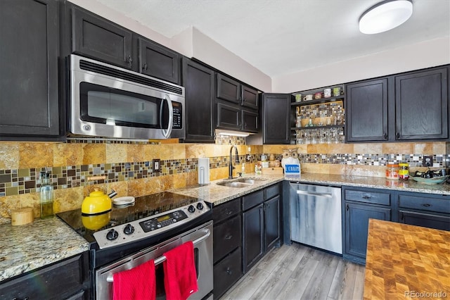 6495 E Happy Canyon Rd Unit 163, Denver, CO 80237 - kitchen featuring appliances with stainless steel finishes, open shelves, backsplash, light stone counters, and light wood finished floors