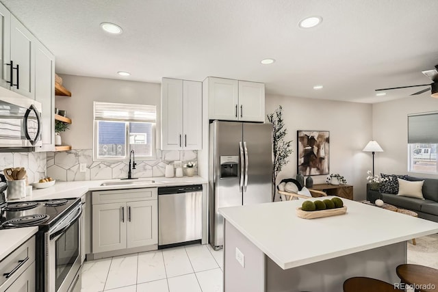 kitchen featuring sink, a kitchen breakfast bar, ceiling fan, stainless steel appliances, and decorative backsplash