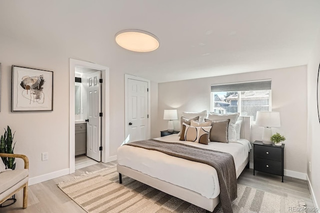 bedroom with connected bathroom and light wood-type flooring