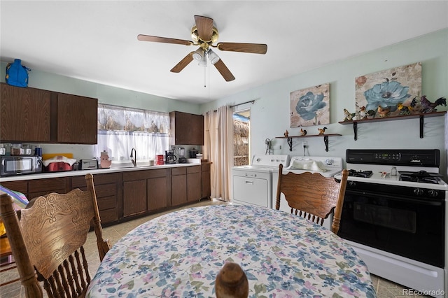 kitchen with white range with gas stovetop, independent washer and dryer, sink, dark brown cabinets, and ceiling fan