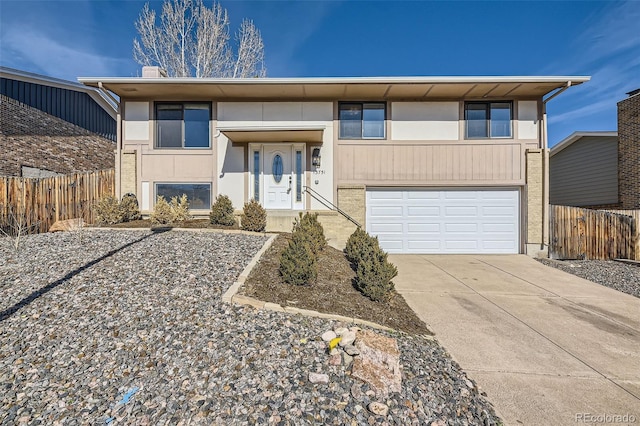 view of front of property featuring a garage, concrete driveway, and fence