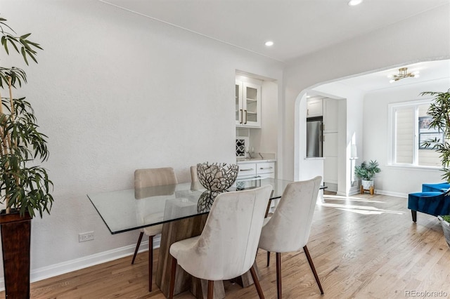 dining area featuring light wood finished floors, baseboards, recessed lighting, an inviting chandelier, and arched walkways