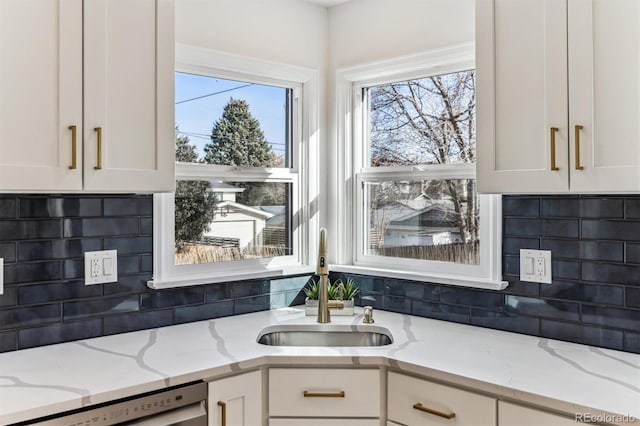 kitchen featuring a wealth of natural light, a sink, white cabinets, and stainless steel dishwasher