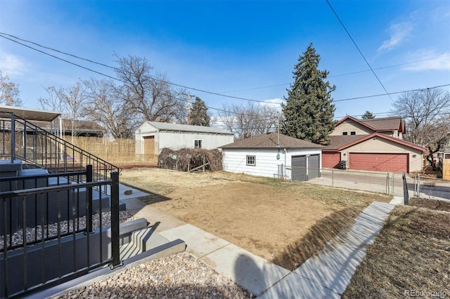 view of yard featuring a garage, stairway, an outdoor structure, and fence