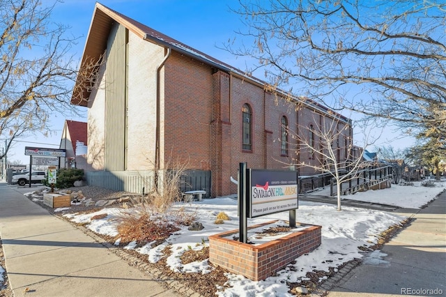 snow covered property with brick siding