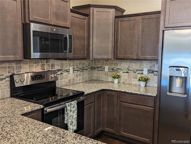 kitchen featuring backsplash, light stone counters, dark brown cabinets, and stainless steel appliances