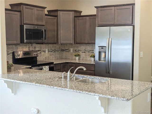 kitchen with light stone countertops, appliances with stainless steel finishes, and sink