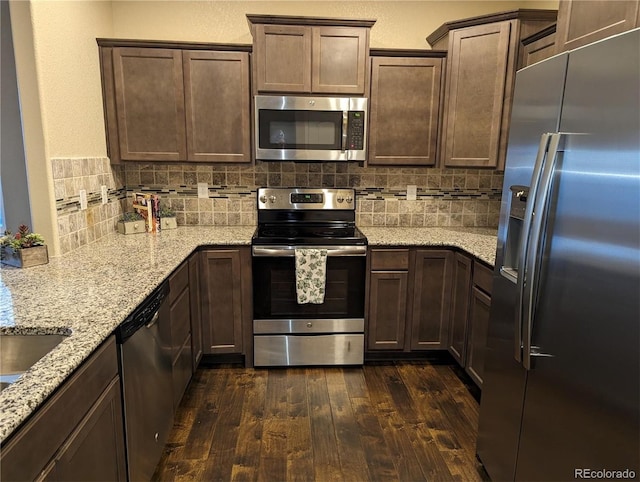 kitchen with light stone countertops, tasteful backsplash, dark brown cabinets, dark hardwood / wood-style flooring, and stainless steel appliances