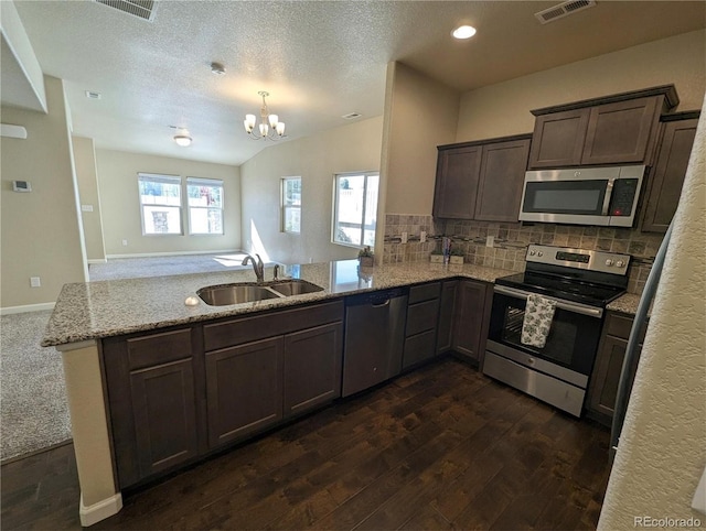 kitchen featuring tasteful backsplash, kitchen peninsula, stainless steel appliances, and dark hardwood / wood-style floors