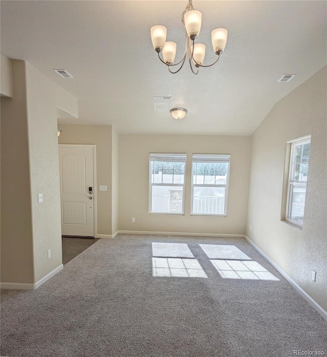 unfurnished room with carpet flooring, an inviting chandelier, and lofted ceiling