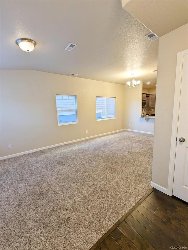 unfurnished room with a chandelier, a textured ceiling, and dark wood-type flooring