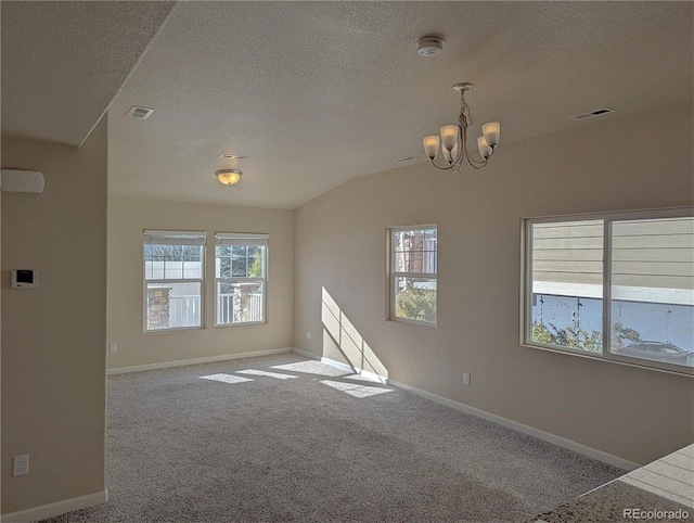 carpeted empty room with an inviting chandelier, a textured ceiling, a wealth of natural light, and vaulted ceiling