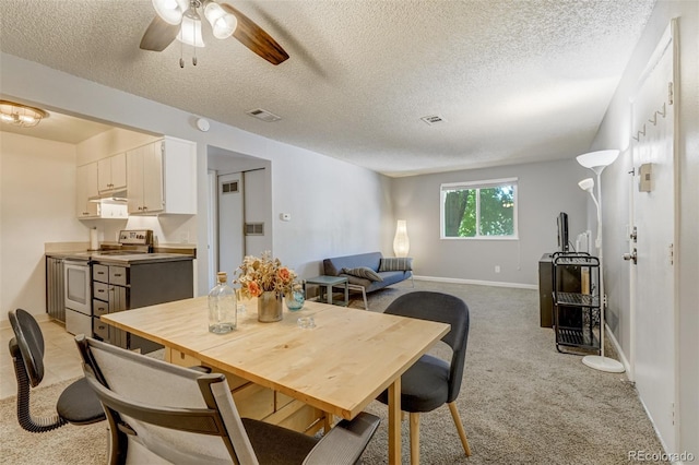 dining space featuring light carpet, ceiling fan, and a textured ceiling