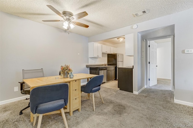 carpeted dining space with ceiling fan and a textured ceiling