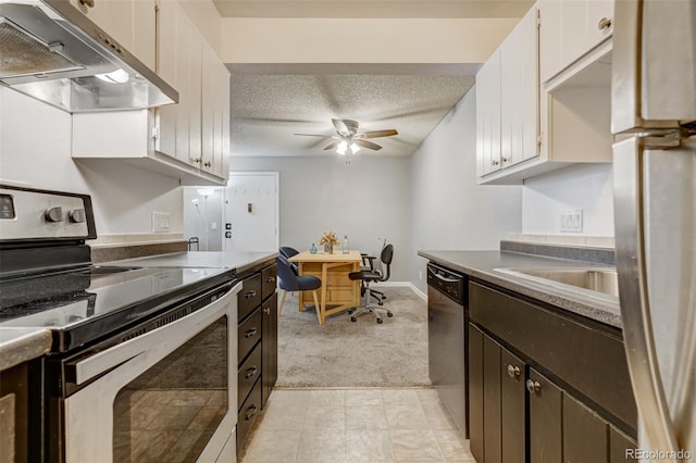 kitchen featuring appliances with stainless steel finishes, a textured ceiling, built in desk, white cabinetry, and range hood