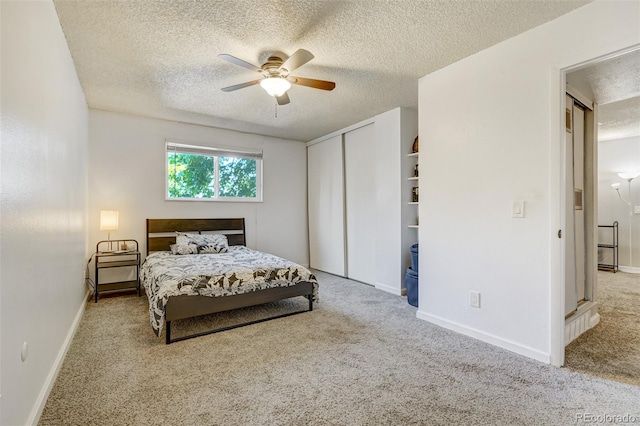 carpeted bedroom with ceiling fan and a textured ceiling