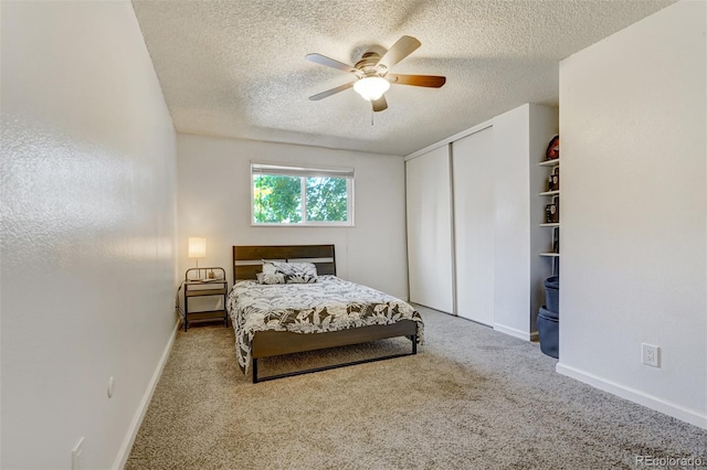 bedroom with ceiling fan, light colored carpet, a textured ceiling, and a closet