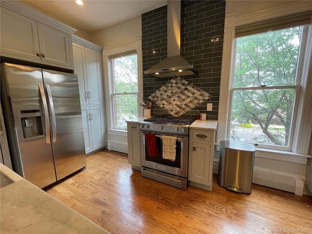 2335 Stout St, Denver, CO 80205 - kitchen with stainless steel appliances, wall chimney exhaust hood, light countertops, light wood-type flooring, and backsplash