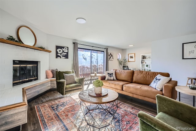 living room with a brick fireplace and wood finished floors