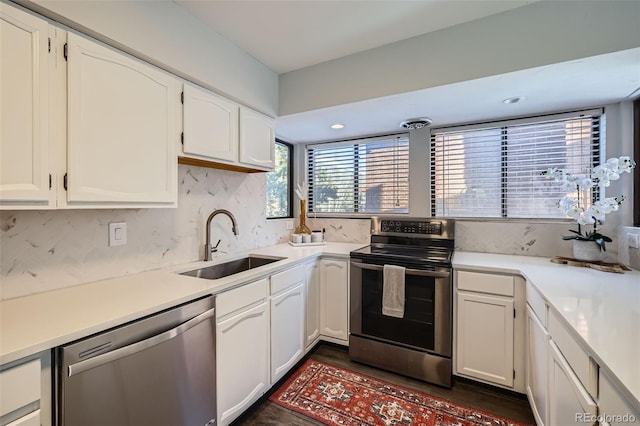 kitchen featuring white cabinets, backsplash, appliances with stainless steel finishes, and a sink