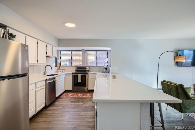 kitchen featuring light countertops, a kitchen breakfast bar, appliances with stainless steel finishes, and a sink