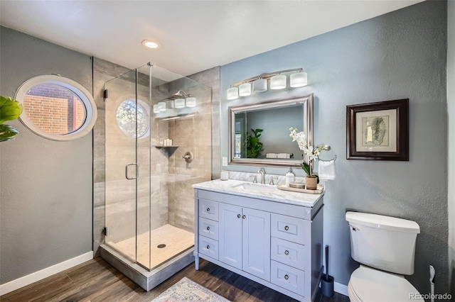 bathroom featuring baseboards, toilet, a stall shower, wood finished floors, and vanity