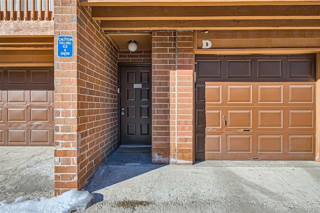 view of exterior entry with brick siding and a garage