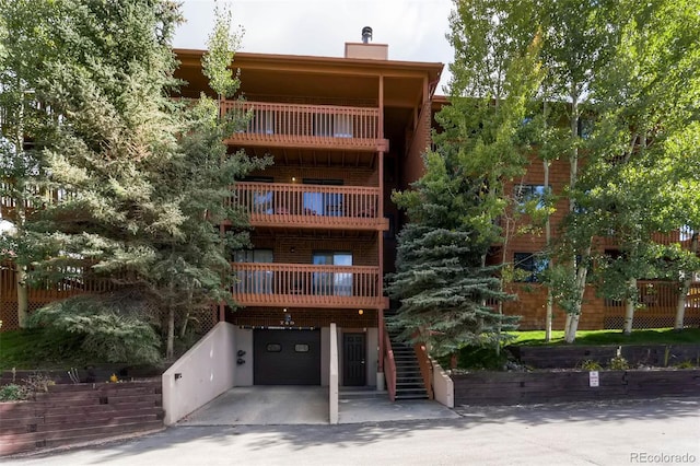 view of property featuring stairway, a garage, and driveway