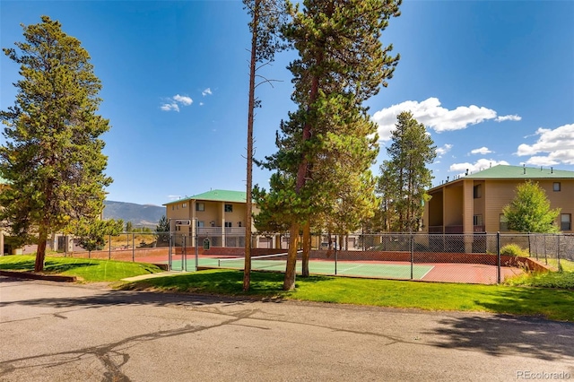 view of property's community featuring a mountain view, a tennis court, and fence