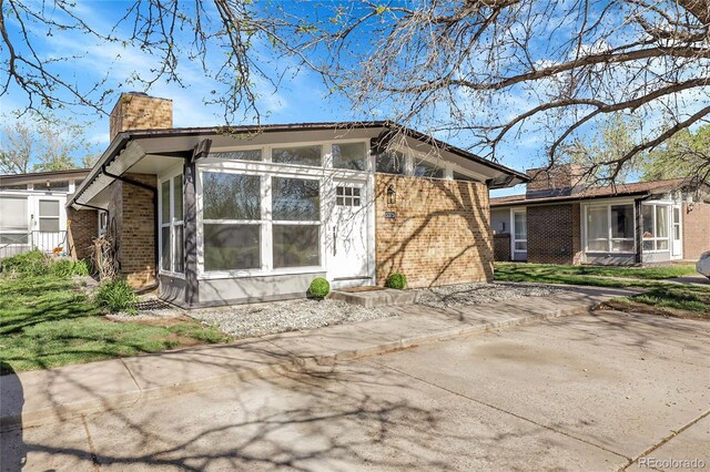 5373 S Prescott St, Littleton, CO 80120 - view of side of property with brick siding, a chimney, and a sunroom