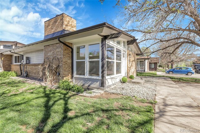 5373 S Prescott St, Littleton, CO 80120 - view of side of home featuring brick siding, a chimney, and a lawn