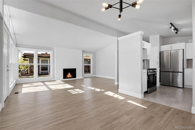 5373 S Prescott St, Littleton, CO 80120 - unfurnished living room with lofted ceiling, a chandelier, light wood-type flooring, baseboards, and a fireplace