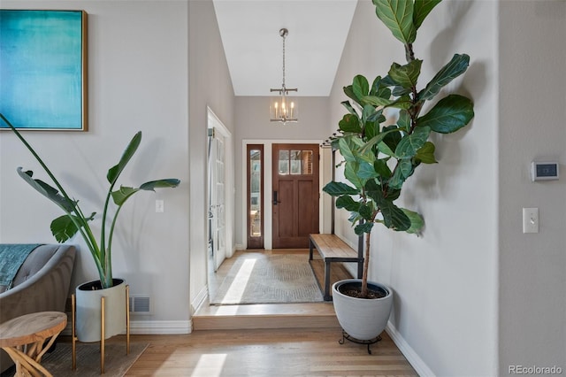 foyer entrance featuring a chandelier, light wood-type flooring, and vaulted ceiling