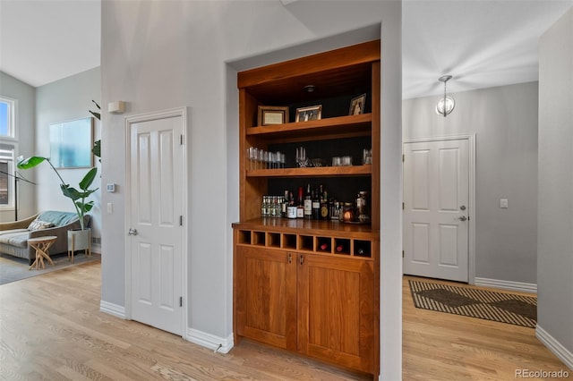 bar featuring decorative light fixtures and light hardwood / wood-style flooring