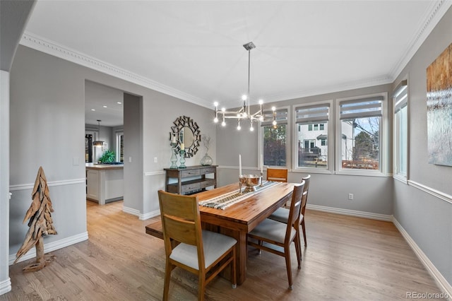 dining area with light hardwood / wood-style flooring, a notable chandelier, and crown molding