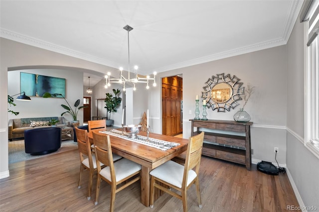 dining area featuring hardwood / wood-style floors, ornamental molding, and a notable chandelier