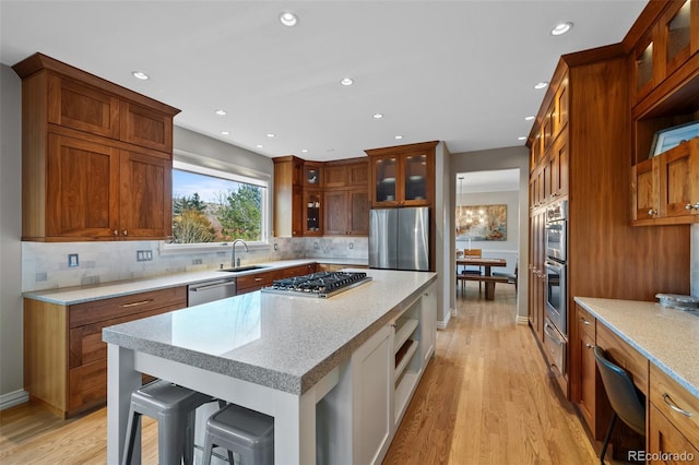 kitchen with a kitchen bar, appliances with stainless steel finishes, sink, light hardwood / wood-style flooring, and a center island