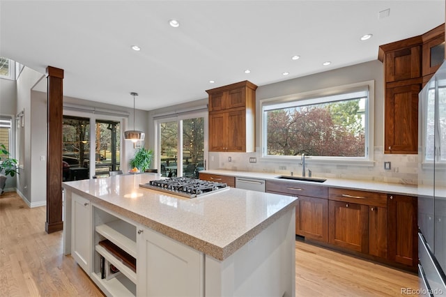 kitchen with light stone counters, stainless steel appliances, sink, pendant lighting, and white cabinetry