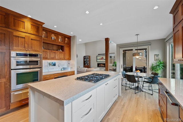 kitchen with backsplash, stainless steel appliances, light hardwood / wood-style floors, white cabinetry, and hanging light fixtures