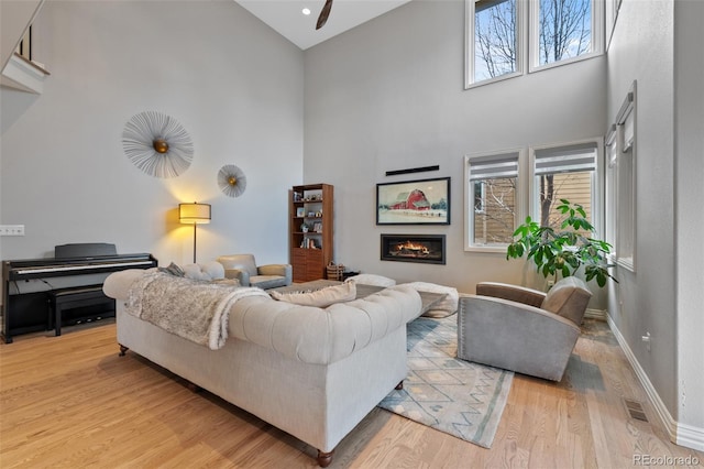 living room with a towering ceiling, light hardwood / wood-style flooring, and a wealth of natural light