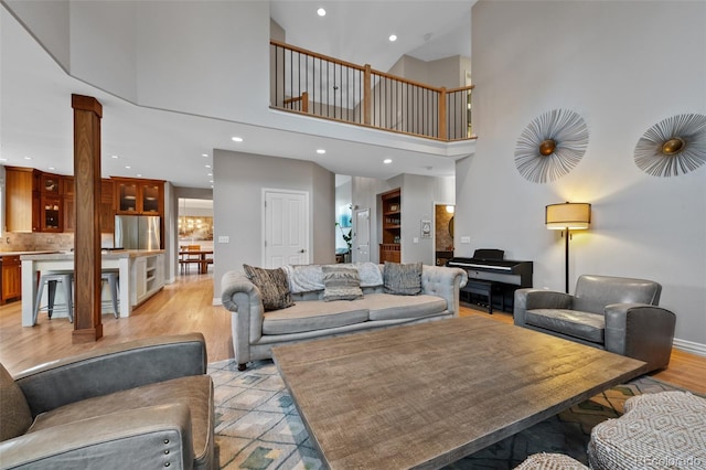 living room with a towering ceiling and light hardwood / wood-style flooring