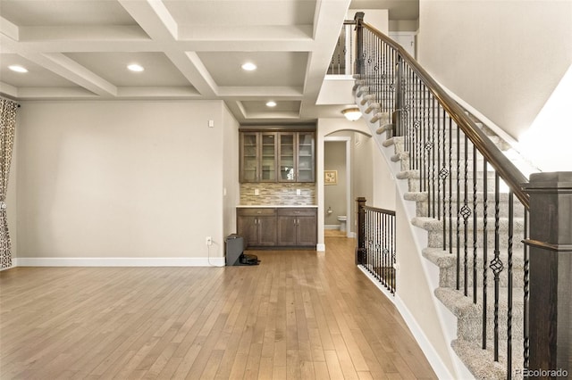 interior space featuring coffered ceiling, light hardwood / wood-style flooring, and beam ceiling